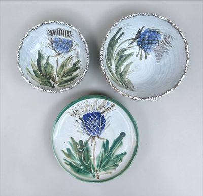 three small bowls with thistle designs on them sitting on a table