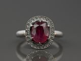 un gros plan d'une bague sertie d'un rubis et de diamants posée sur une surface réfléchissante