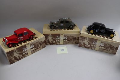 trois petites voitures sont posées sur des cartons, sur une table