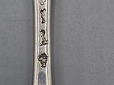 an old silver spoon with writing on it sitting on a table
