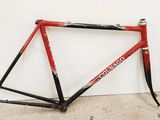 une photo d'un vélo rouge et noir appuyé contre un mur blanc