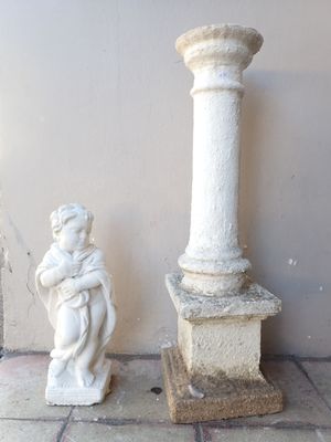 a statue of a boy holding a baby next to a pillar