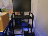 a computer on a cart in a room with boxes and a map on the wall