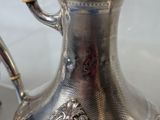 a silver coffee pot with a handle on a table