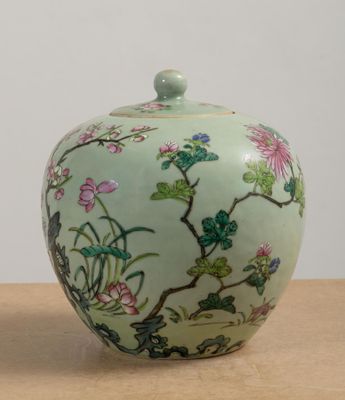 a green vase sitting on a table with a white wall in the background