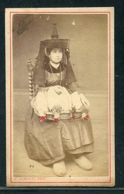 une vieille photo d'une femme assise sur une chaise, tenant un bébé dans ses bras