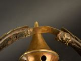 a brass bell with a birdhouse on top of it