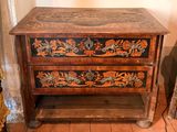 a wooden chest of drawers with floral designs on it