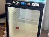 un petit réfrigérateur avec une porte vitrée dans une pièce