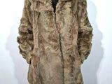 a man in a fur coat standing in front of a white wall