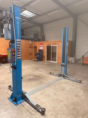 deux ponts élévateurs bleus dans un garage, avec un camion rouge en arrière-plan