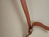 a tan purse with a brown strap hanging from it ' s handle