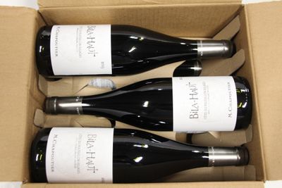 three bottles of wine are in a cardboard box on a table