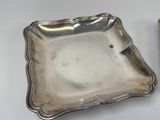 two silver plated dishes on a white table with a silver spoon