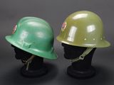 two green helmets on a black mannequin head on a gray background