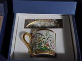 a coffee cup in a box with a gold handle