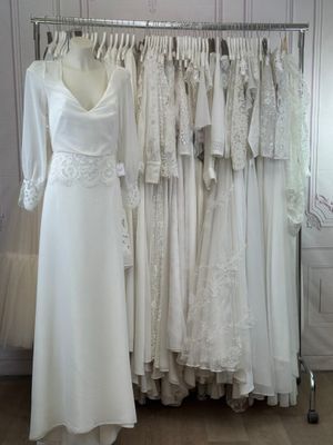 many wedding dresses hanging on a rack in a room
