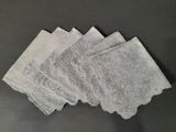 quatre serviettes blanches ornées de dentelle posées sur une table