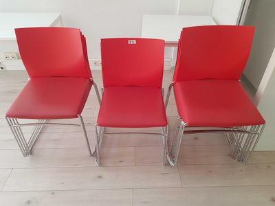 three red chairs sitting next to each other on a wooden floor