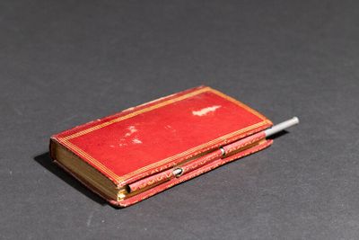 un petit livre rouge d'où dépasse une cigarette