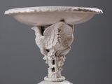 a white vase with a bird on it on a table