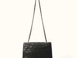 un sac Chanel noir auquel est suspendue une chaîne