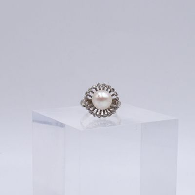 une image représentant une bague ornée d'une perle et d'un diamant posée sur un cube transparent