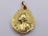 a close up of a gold coin with a woman on it