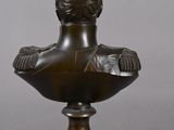 a bronze bust of a man on a wooden base