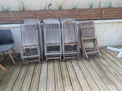 four chairs sitting on a wooden deck next to a planter