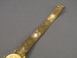 une image représentant une montre-bracelet en or sur laquelle repose une pièce de monnaie