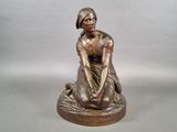 bronze statue of a woman sitting on a rock with her hands on her knees