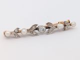 un gros plan sur une broche ornée de perles et de diamants