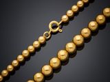 a gold bead necklace on a black background