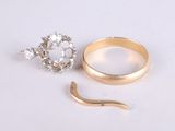 a gold ring and a diamond ring on a white surface