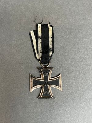 un gros plan d'une croix en métal ornée d'un ruban noir et blanc