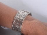 a woman ' s hand with a silver bracelet on it
