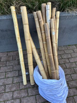 un grand nombre de tiges de bambou dans un sac posé par terre