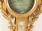 a gold clock with a thermometer in the middle of it