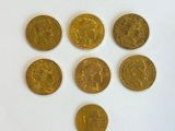 six types différents de pièces d'or sont disposés sur une surface blanche