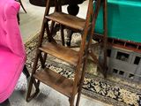 une chaise rose et un tabouret en bois dans une pièce