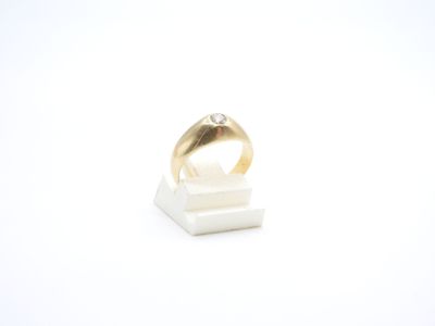 un gros plan d'une bague posée sur un support, sur une surface blanche