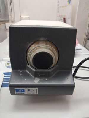 un petit appareil photo posé sur une table, avec un cordon