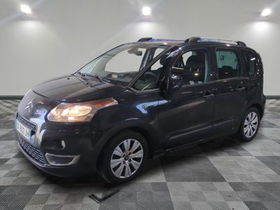 La petite camionnette noire est garée sur un sol en carrelage à damier.