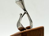 sculpture of a silver ring on a wooden stand against a white background