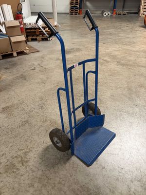 a blue hand truck that is sitting in a warehouse