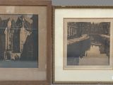 two framed photographs of buildings and a river in a room