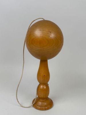 une boule en bois posée sur un socle en bois et attachée à une cordelette
