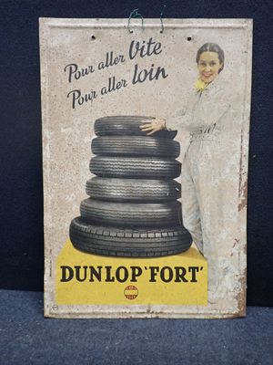 une vieille enseigne en tôle faisant la promotion des pneus Dunlop sur fond bleu