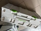 a white box with a green handle sitting on a tiled floor